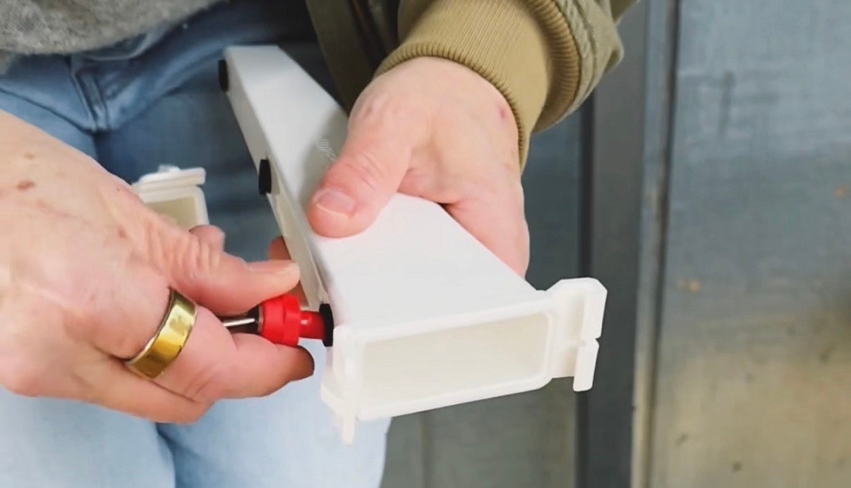 Close-up of hands attaching drinking drippers to the Chicken Fountain arm during installation.