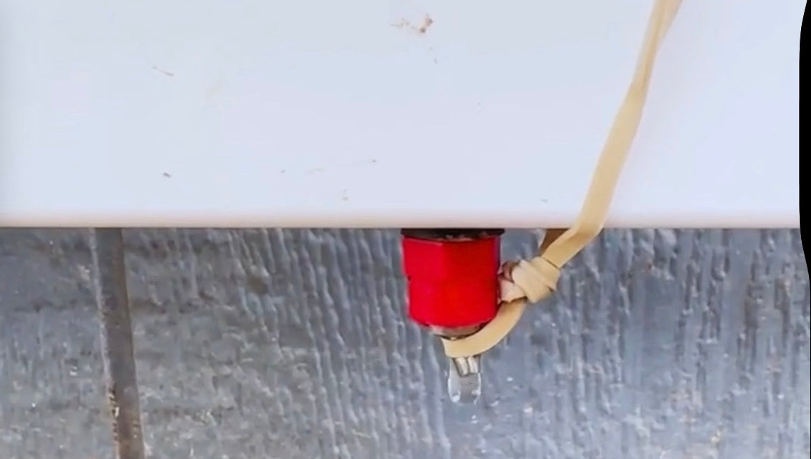 Close-up of rubber band wrapped around Chicken Fountain arm keeping dripper open to train chickens to use the automatic waterer.